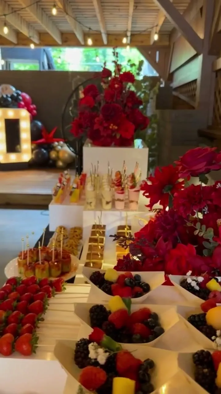 Dessert table under red rose installations at a rustic lattice venue