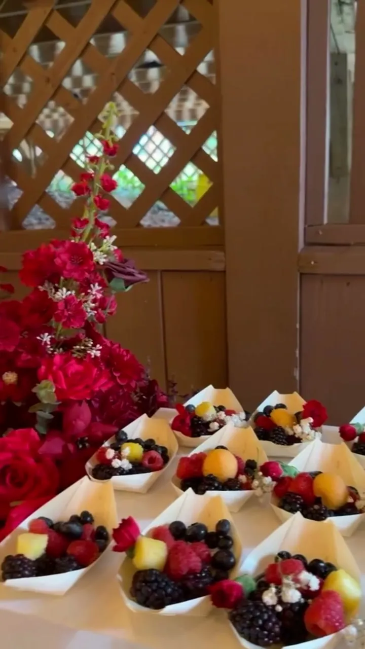 Fruit tarts and berry cups beside red roses