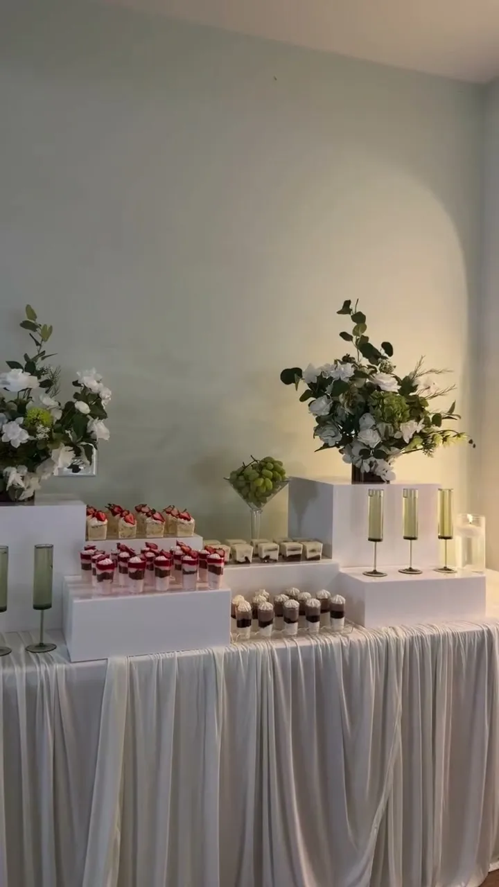 Minimal all-white dessert table with greenery