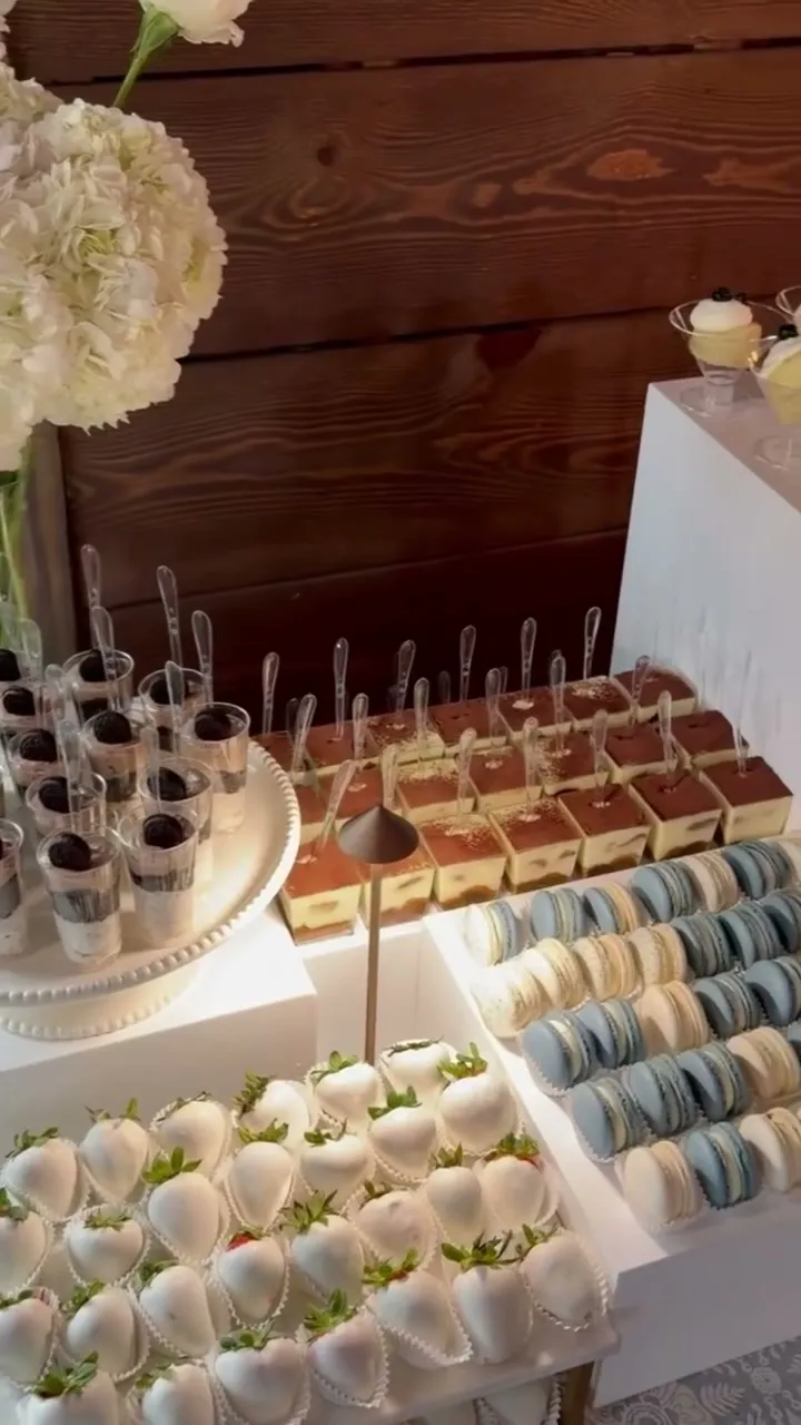 Candlelit wedding dessert table against a barn-wood wall with blue and white sweets