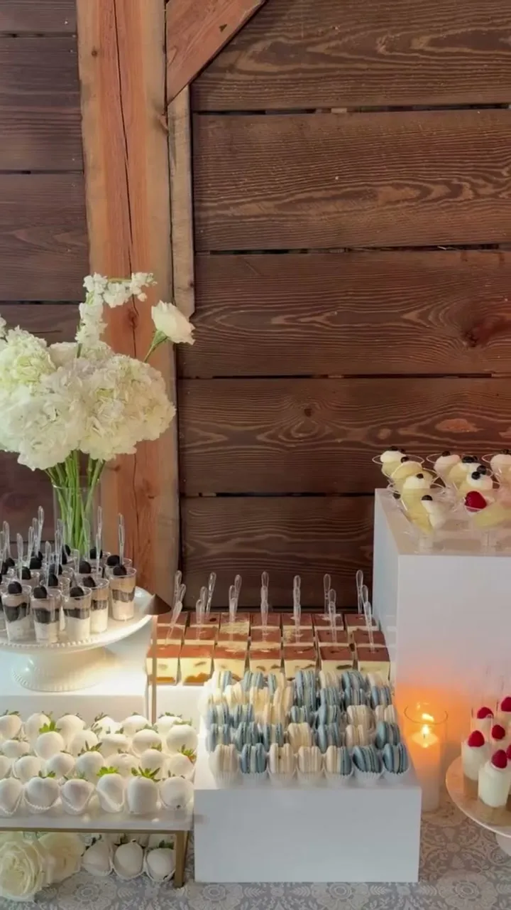 Wide view of a rustic wedding dessert table with taper candles