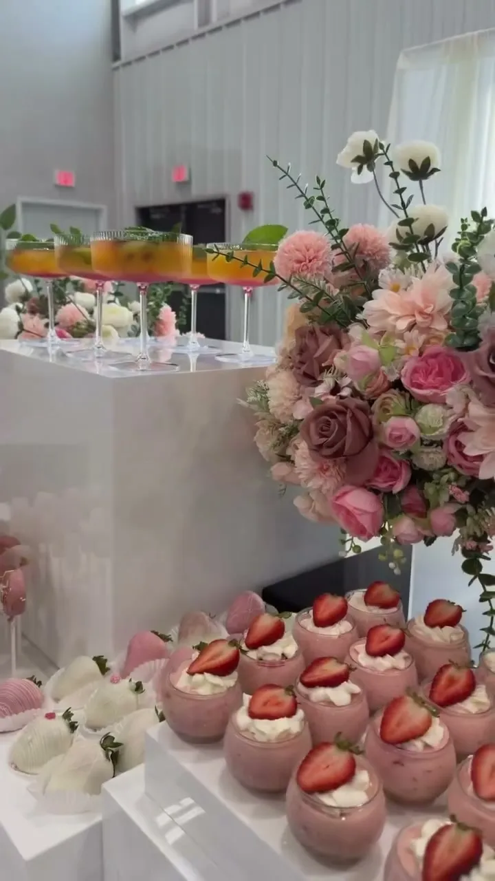 Blush roses on white acrylic plinths over a dessert table