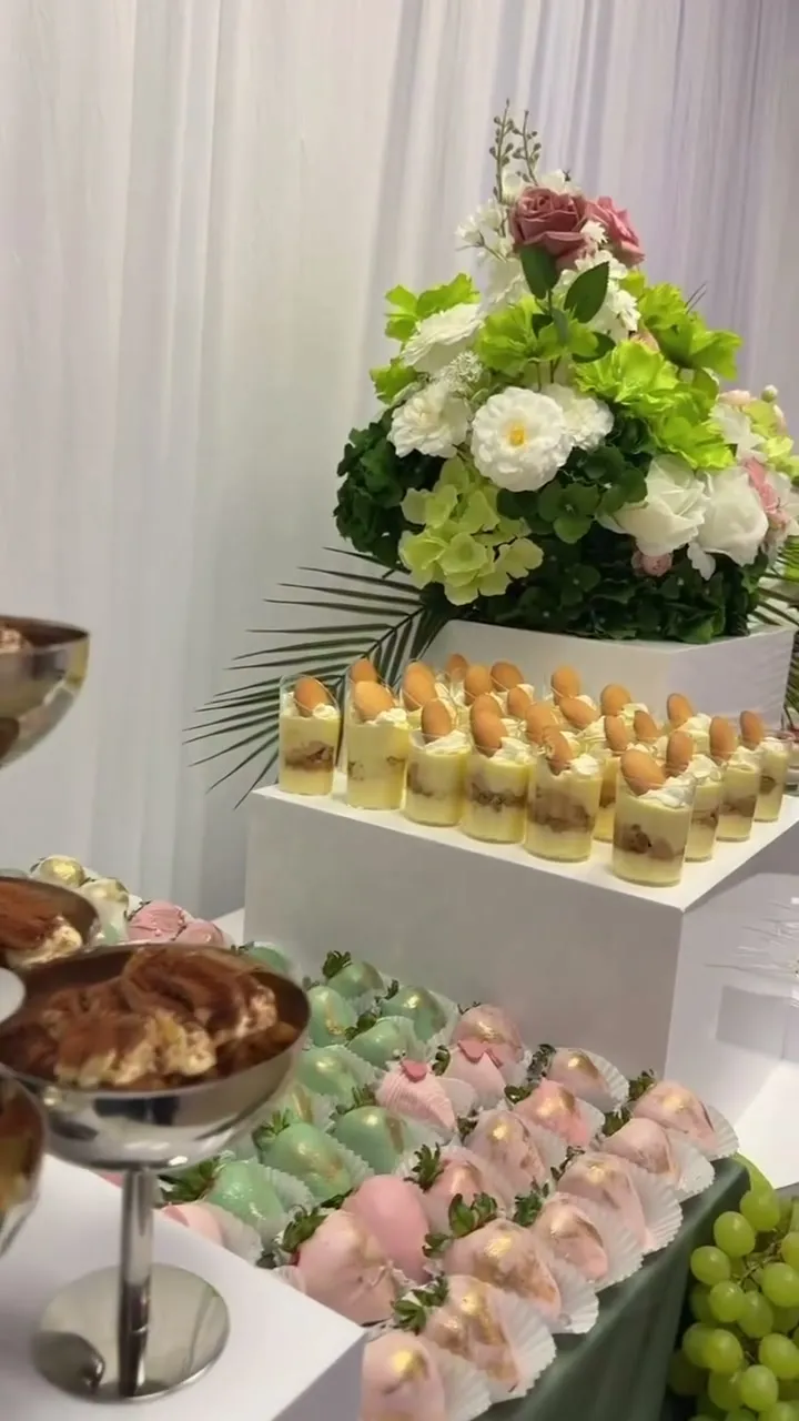 Tiered dessert table with green hydrangeas and tropical leaves