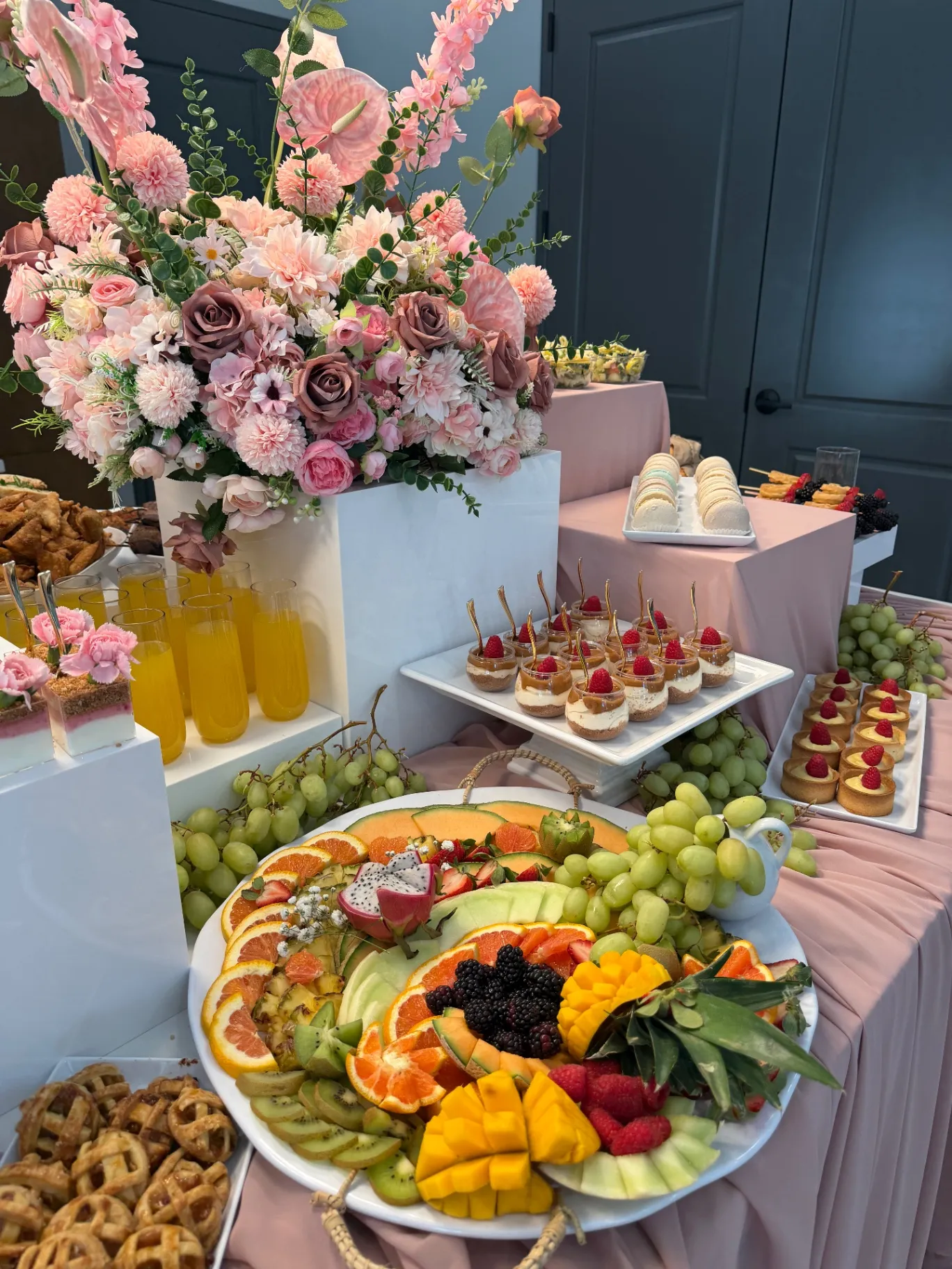 Blush floral dessert table with brûlée cups, tarts and a fruit platter